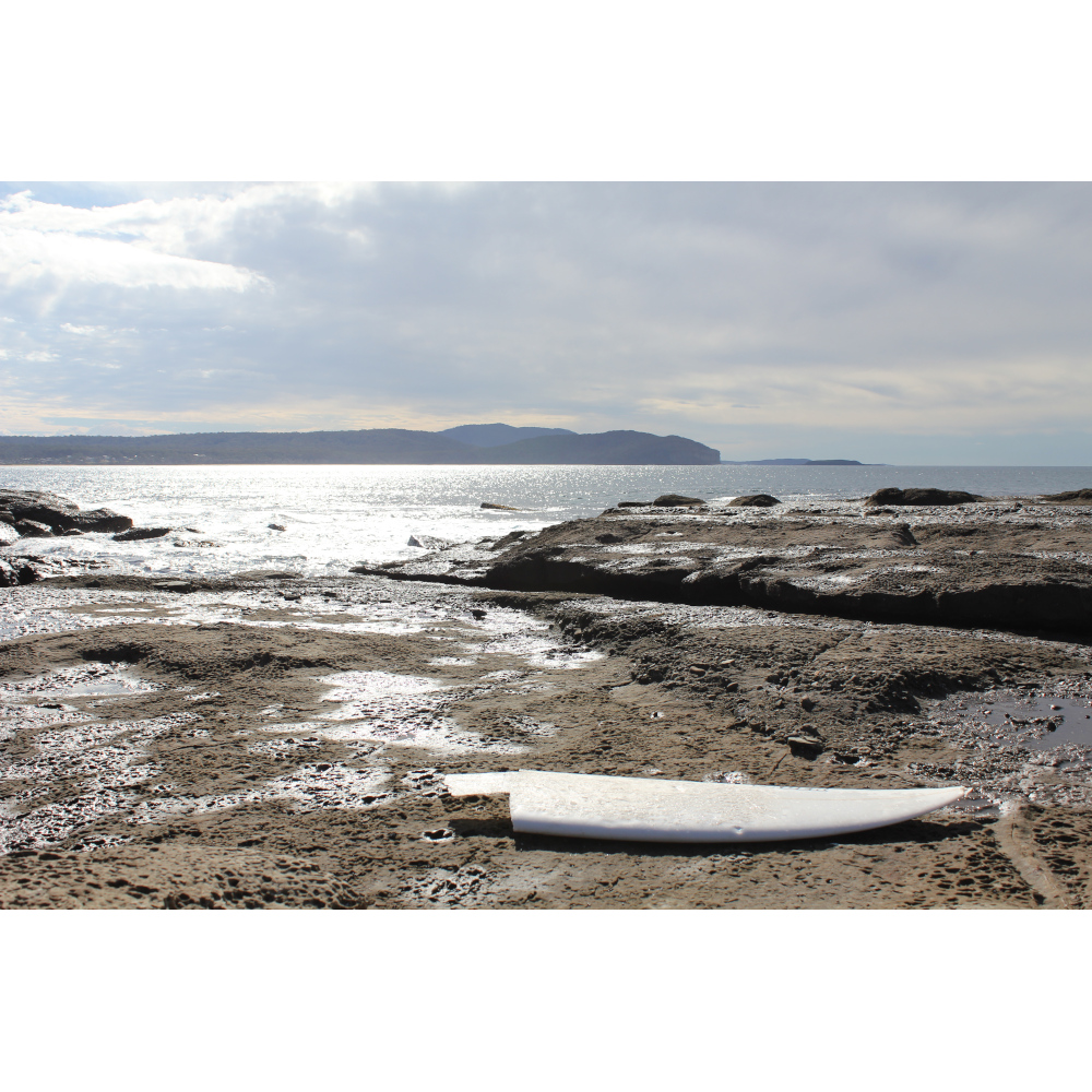 Broken surfboard washed up on to rocks