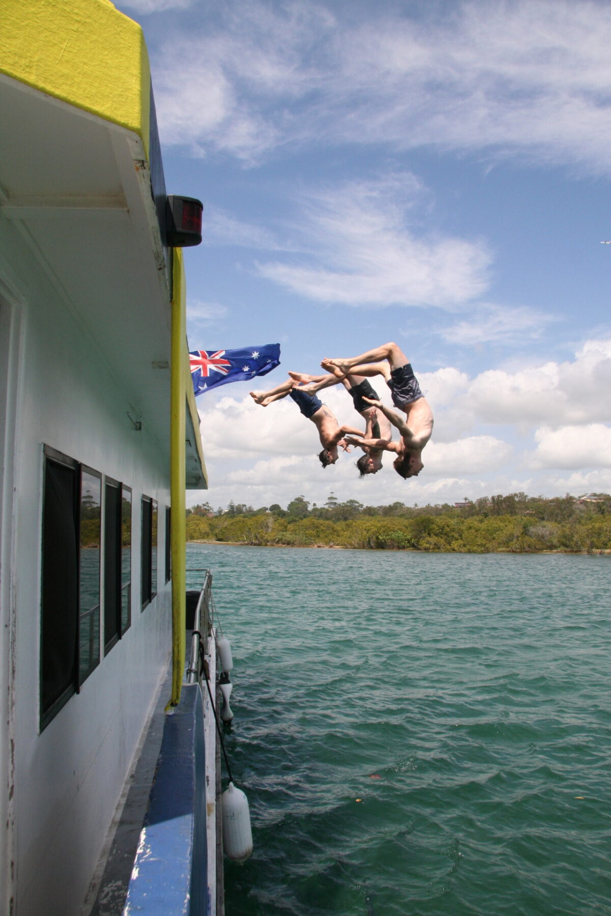 3 boys diving backwards off a boat